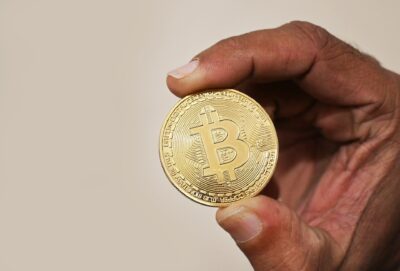 Mão segurando uma moeda física representando o Bitcoin